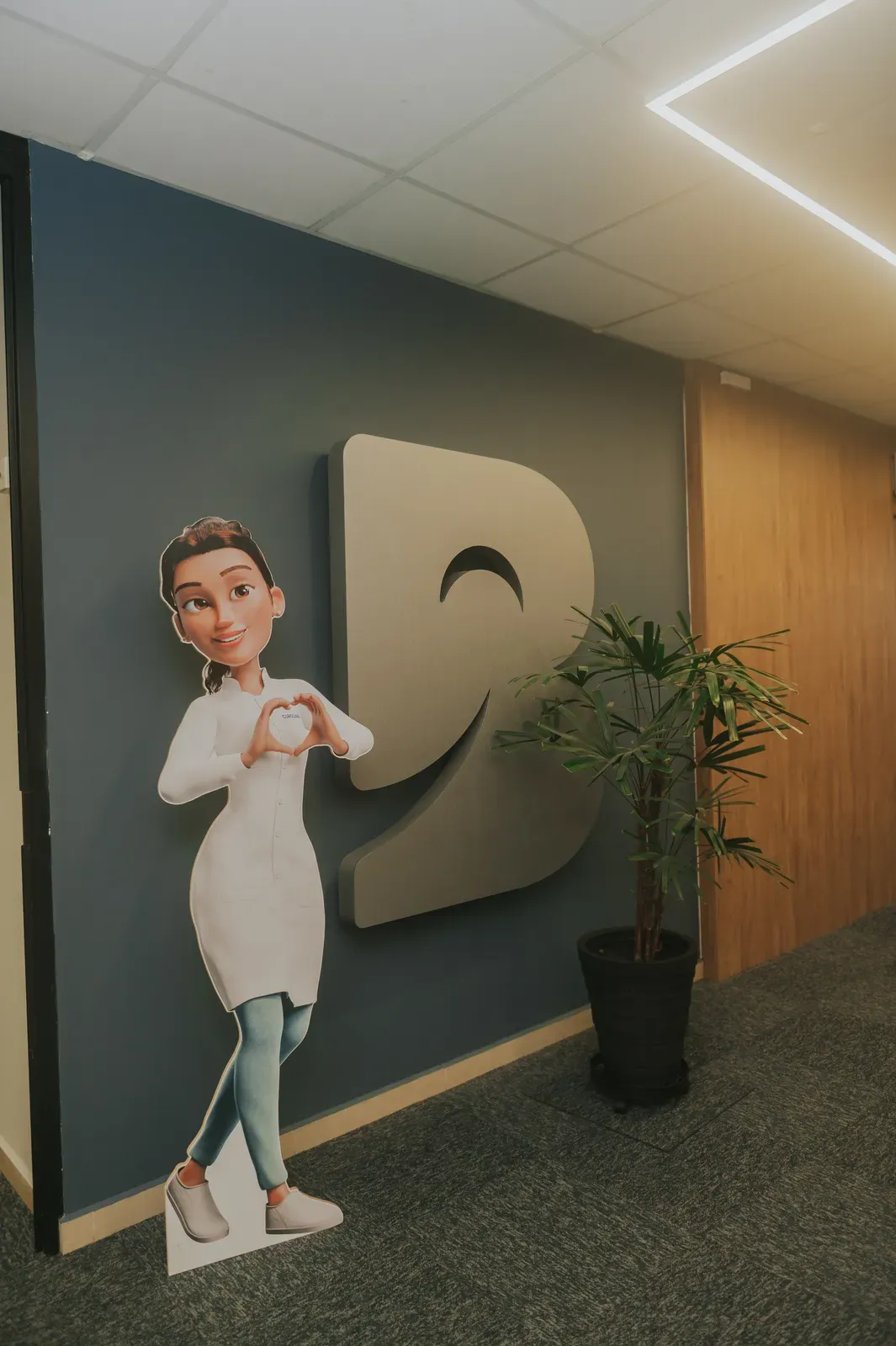 A Mari, assistente da escola, em tamanho real na entrada, ao lado do logotipo